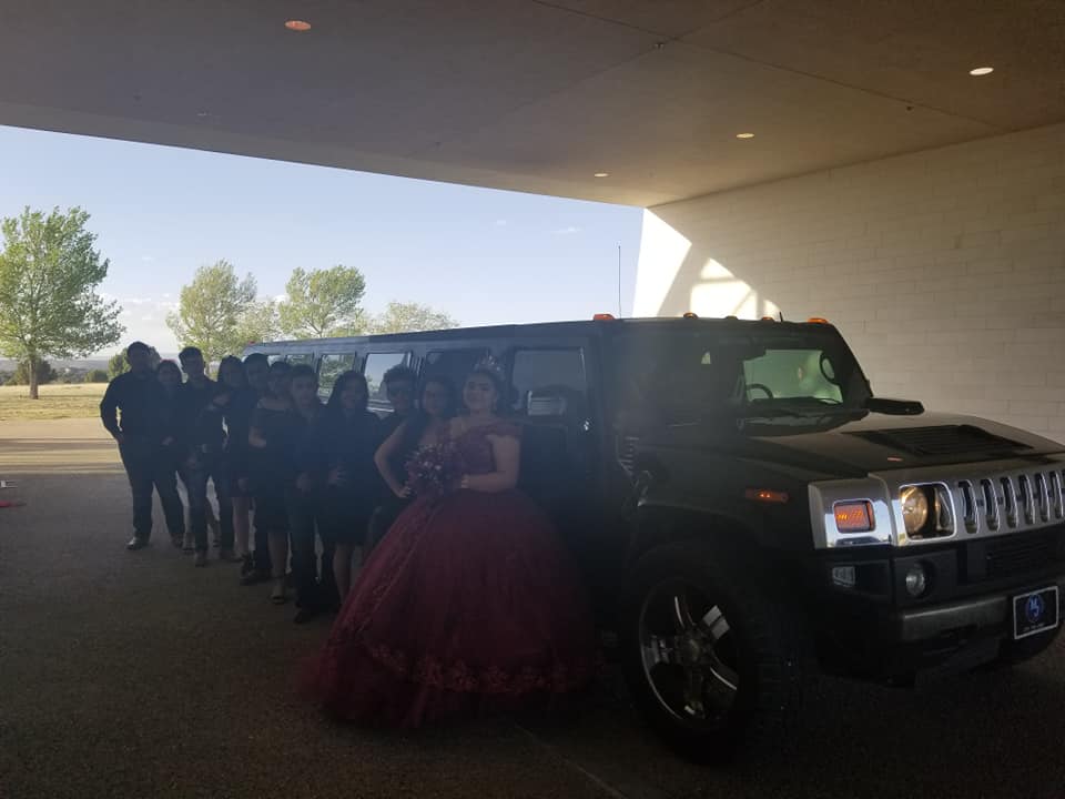 Quinceañera in burgundy with court boarding the Hummer limo
