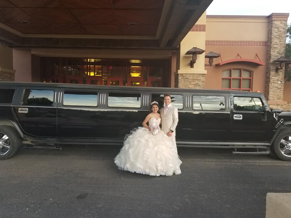 Quinceañera and chambelán in front of the Hummer limo